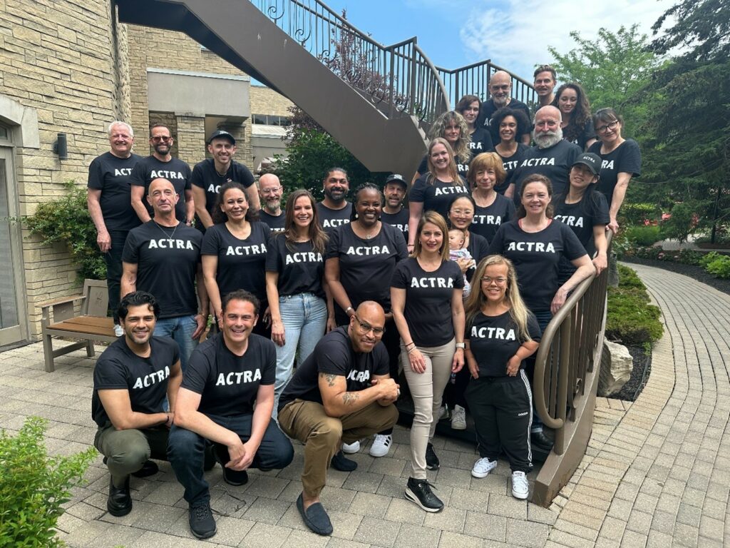 Image of a group of people wearing black shirts that read ACTRA on them. The group smiles and faces the camera. 